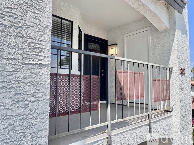 A balcony with a metal railing and a red cushioned chair.