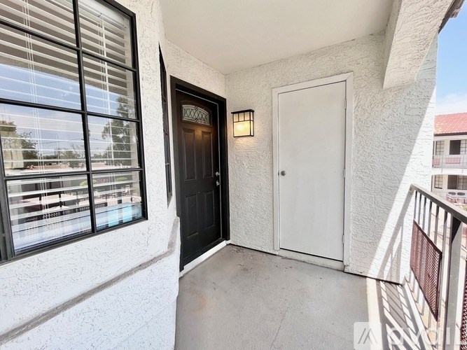 A balcony with a black door and a white door.