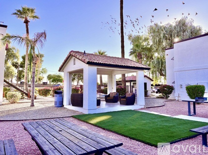 A white house with a red roof and a patio with a table and chairs.