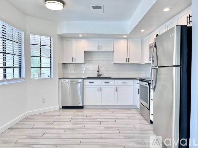 A kitchen with white cabinets and a refrigerator.