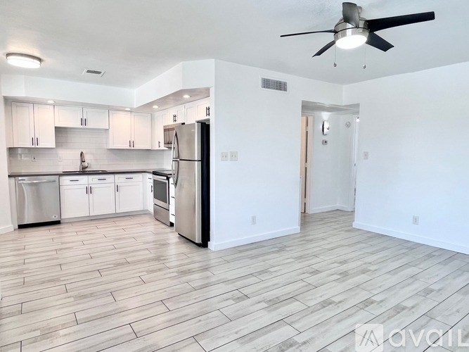 A spacious kitchen with a refrigerator, cabinets, and a ceiling fan.