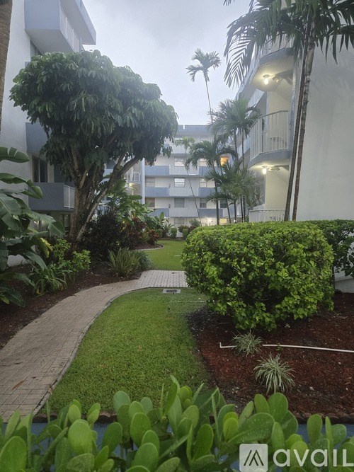 A garden with a pathway, green plants, and a building in the background.