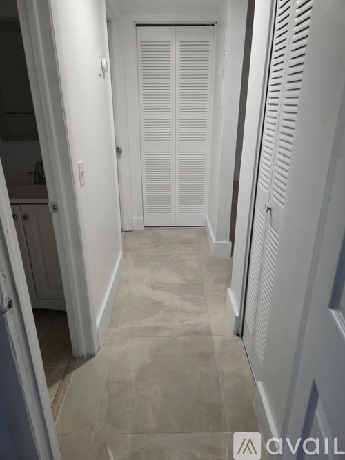 A hallway with a white door and a tiled floor.