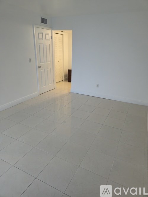 A room with a white door and tiled floor.