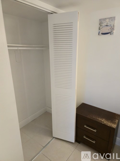 A white closet with a brown desk and a picture on the wall.
