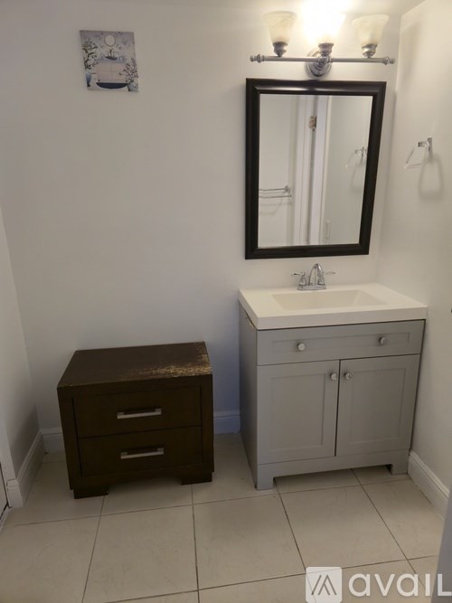 A bathroom with a sink, mirror, and two drawers.