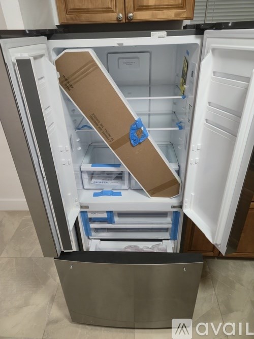 A cardboard box is taped to the inside of an open refrigerator.