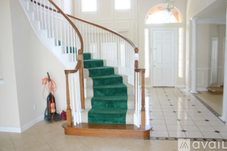 A staircase with a green carpeted runner and wooden balusters.
