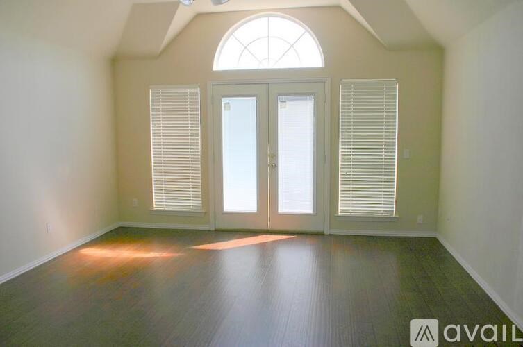 A room with a large arched window and two doors.