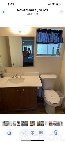 A man is taking a selfie in a bathroom with a white toilet and sink.