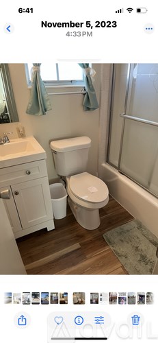 A white toilet is placed in a bathroom with a white sink and a window with a blue towel hanging on it.