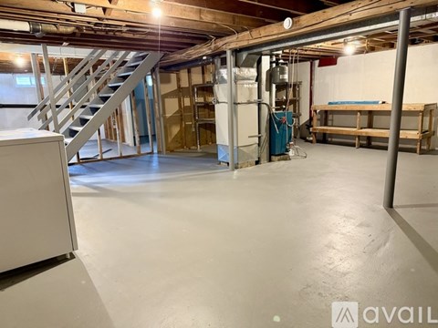 A spacious room with a staircase and a white cabinet on the left side.