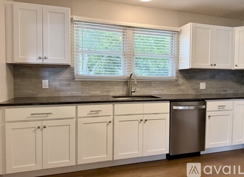 A kitchen with white cabinets and a black countertop.