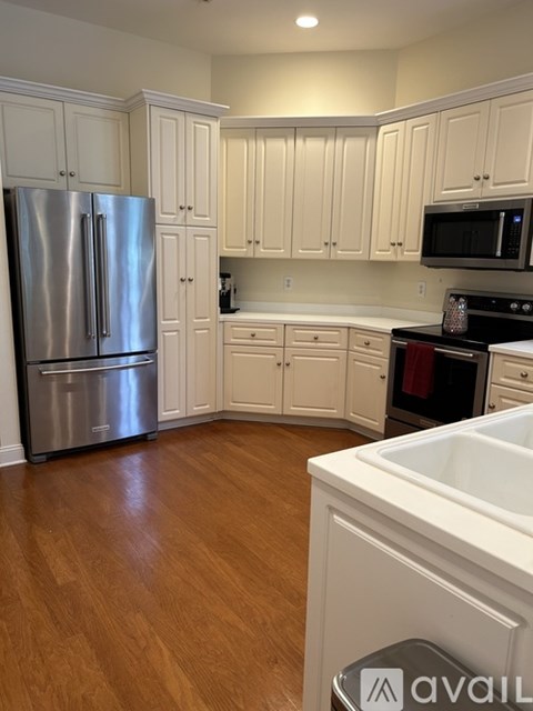 A kitchen with white cabinets and a stainless steel refrigerator.