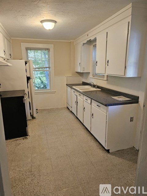 A kitchen with white cabinets and a black refrigerator.