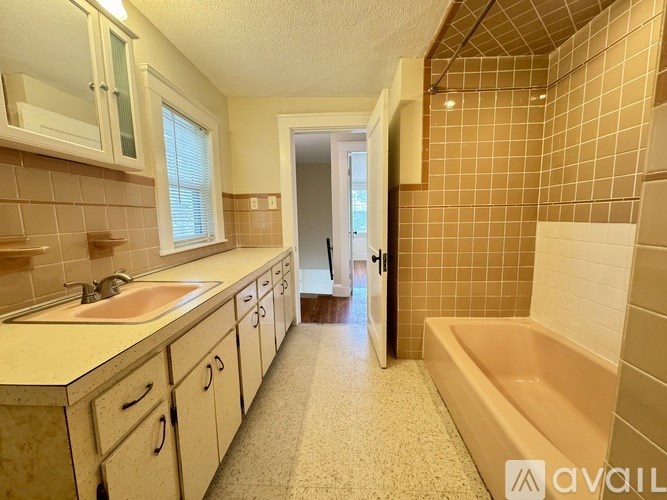 A room with wooden floors and a window overlooking a green area.