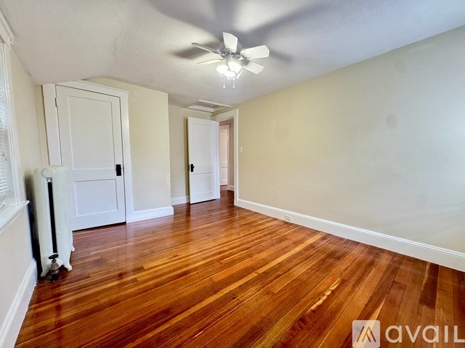 A hallway with a wooden floor and a rug in the foreground.
