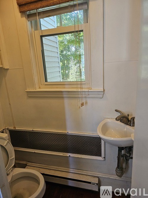 A bathroom with a toilet, sink, and window.
