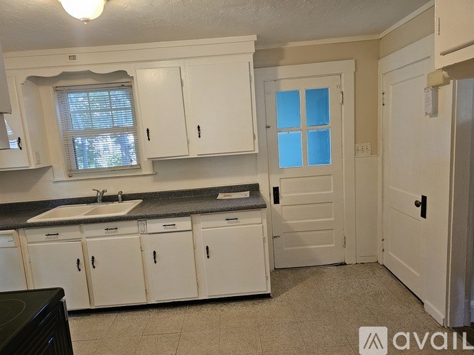 A kitchen with white cabinets and a black counter.