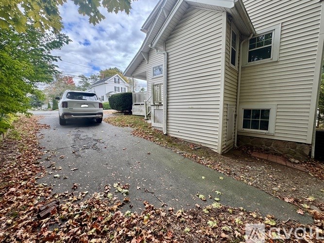 A hallway with a wooden floor and white staircase.