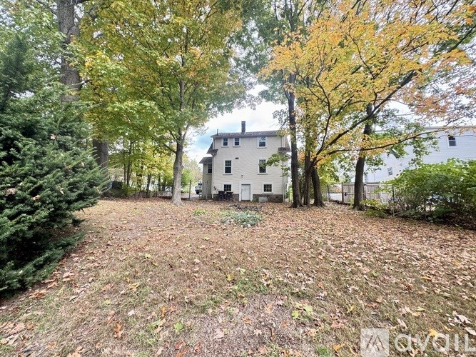 A white house is surrounded by trees with yellow leaves.