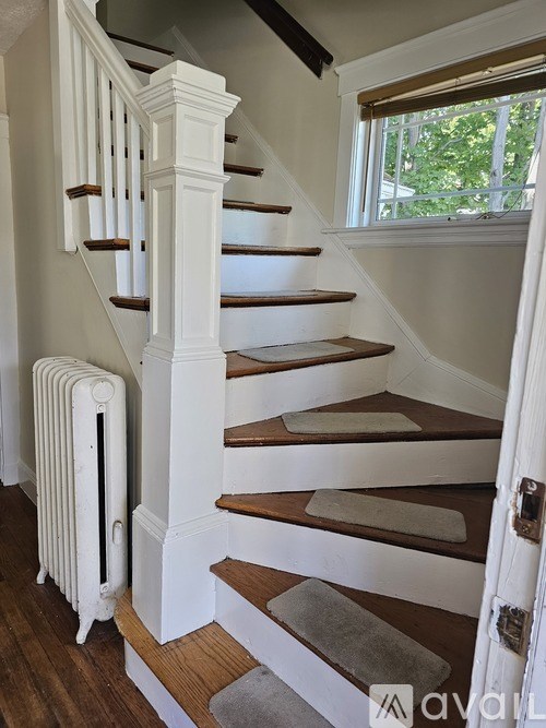 A white staircase with a radiator on the side.