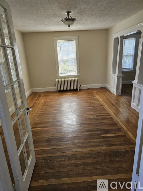 A room with wooden floors and a window with a white frame.