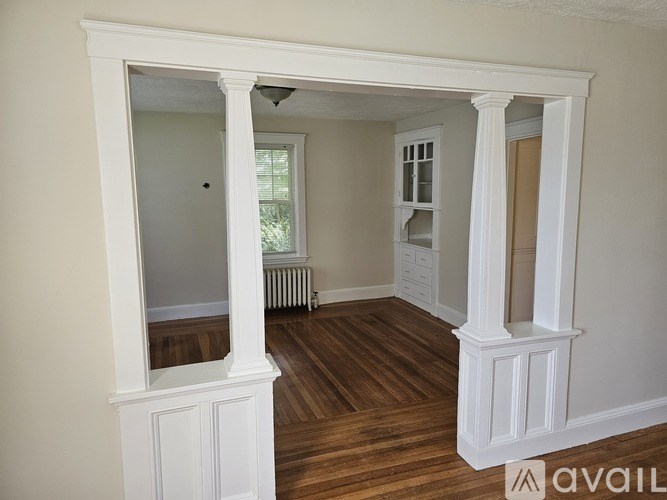 A room with white columns and wooden flooring.