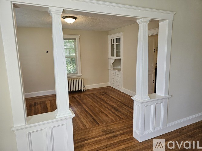 A room with white columns and wooden flooring.