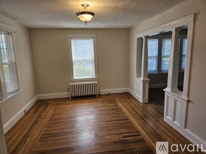 A room with wooden floors and a window with blinds.