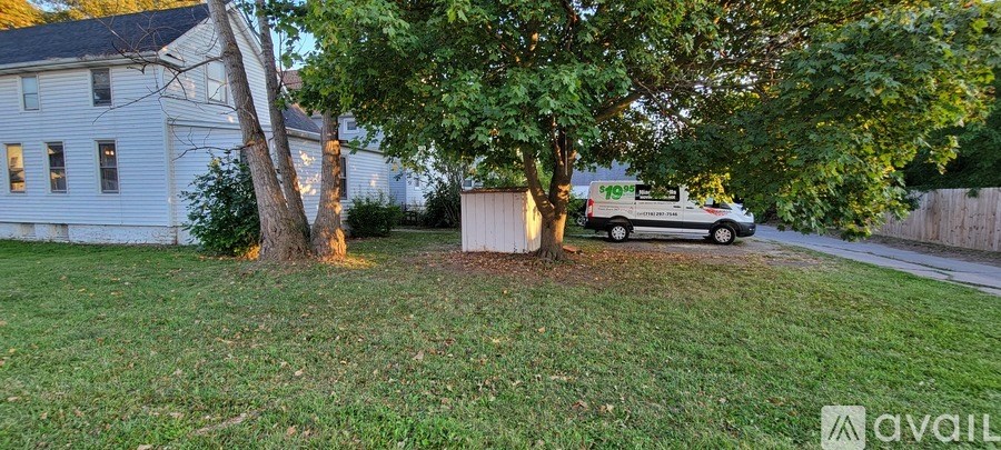 A white van is parked in a driveway next to a tree.