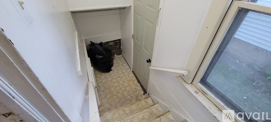A black bag is sitting in a small white closet.