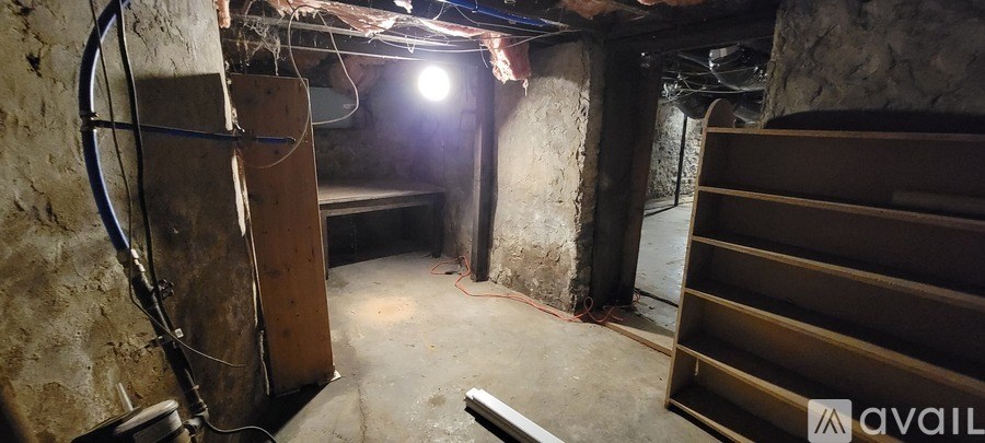 A dark, unfinished basement with a light source in the middle.