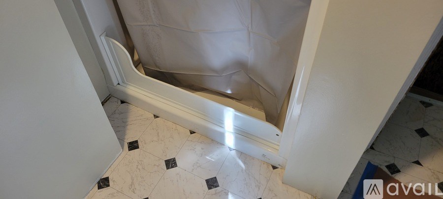 A bathroom with a shower curtain and tiled floor.