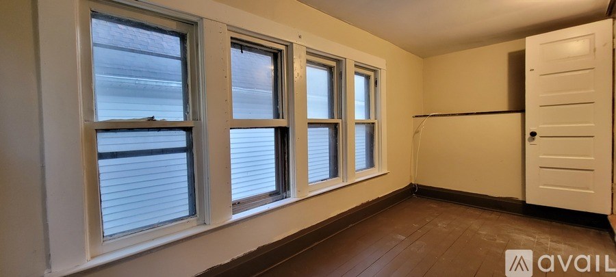A room with a white door and three windows with blinds.