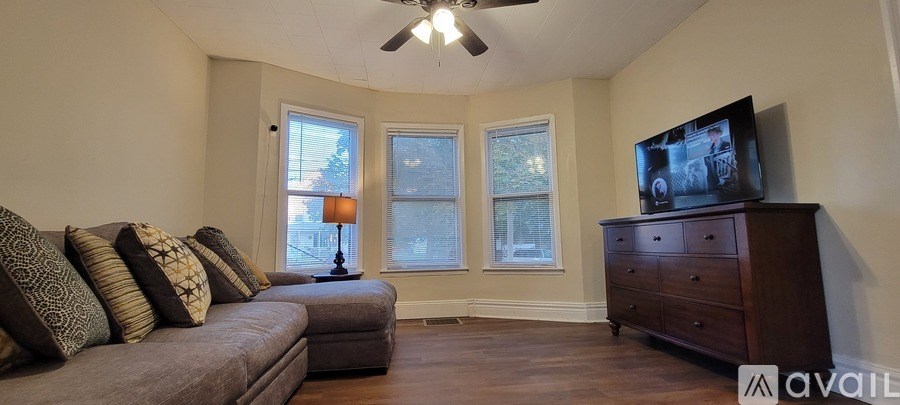 A living room with a grey couch, a television, and a ceiling fan.