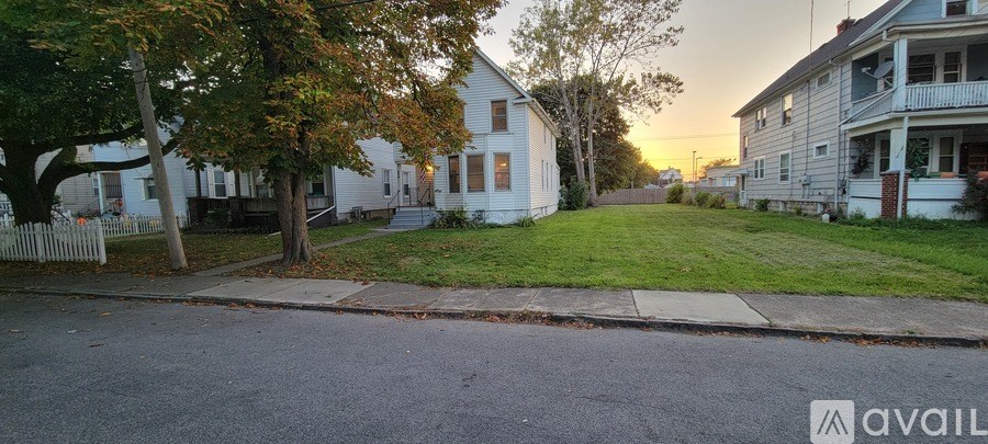 A quiet street with houses on both sides and a tree in the foreground.