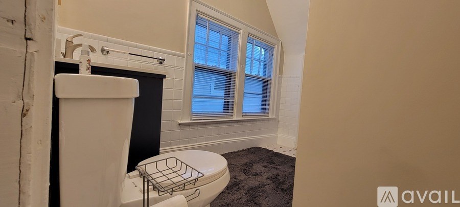 A bathroom with a toilet, sink, and a window.