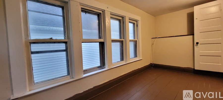 A room with three windows and a door is available for rent.