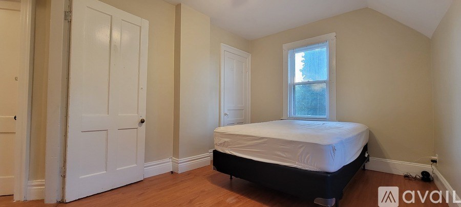A bedroom with a bed, a window, and a door.