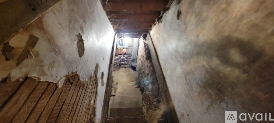A long, narrow staircase with wooden steps and walls covered in dust and debris.