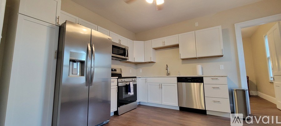 A kitchen with a stainless steel refrigerator and white cabinets.