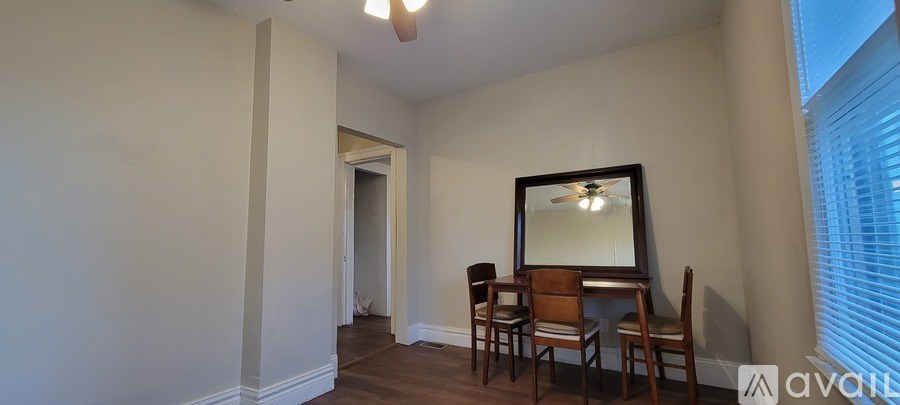 A room with a wooden floor, a chair, a table and a mirror.