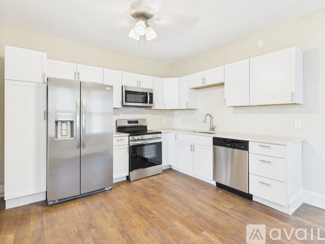 A kitchen with white cabinets and a wooden floor.