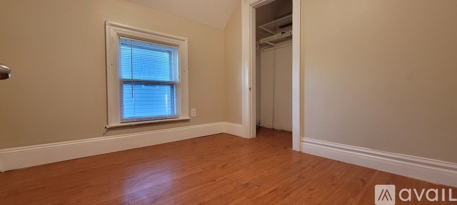 A room with a window and wooden floors is available for rent.