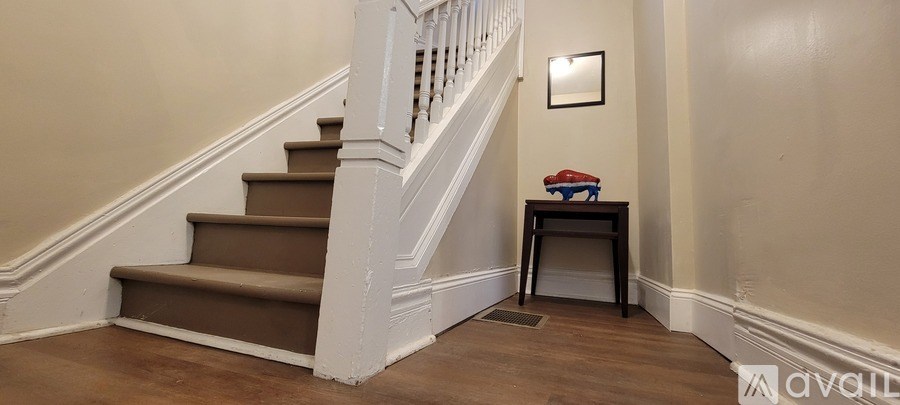 A staircase with a table and a mirror on the wall.