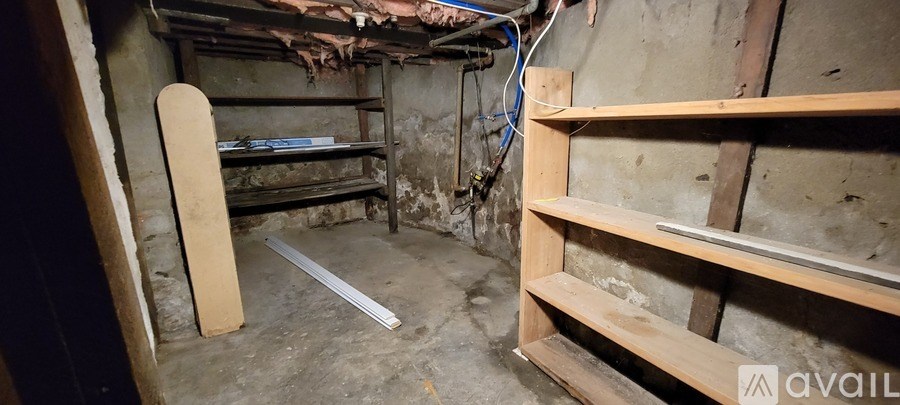 A room with a shelf and a skateboard leaning against the wall.