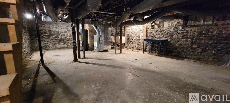 A dark, unfinished basement with stone walls and exposed pipes.