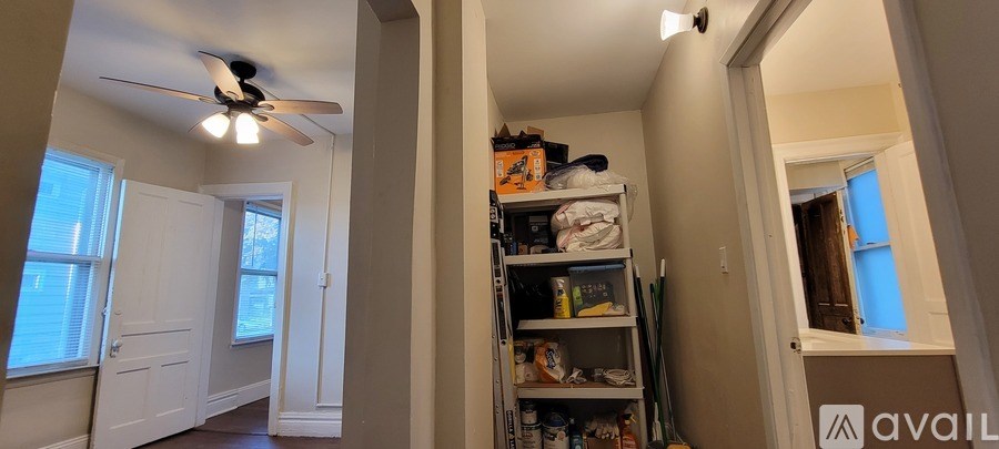 A room with a ceiling fan and a shelf with items on it.