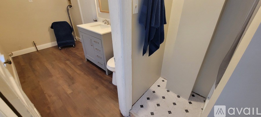 A bathroom with a toilet, sink, and a blue towel hanging on the wall.